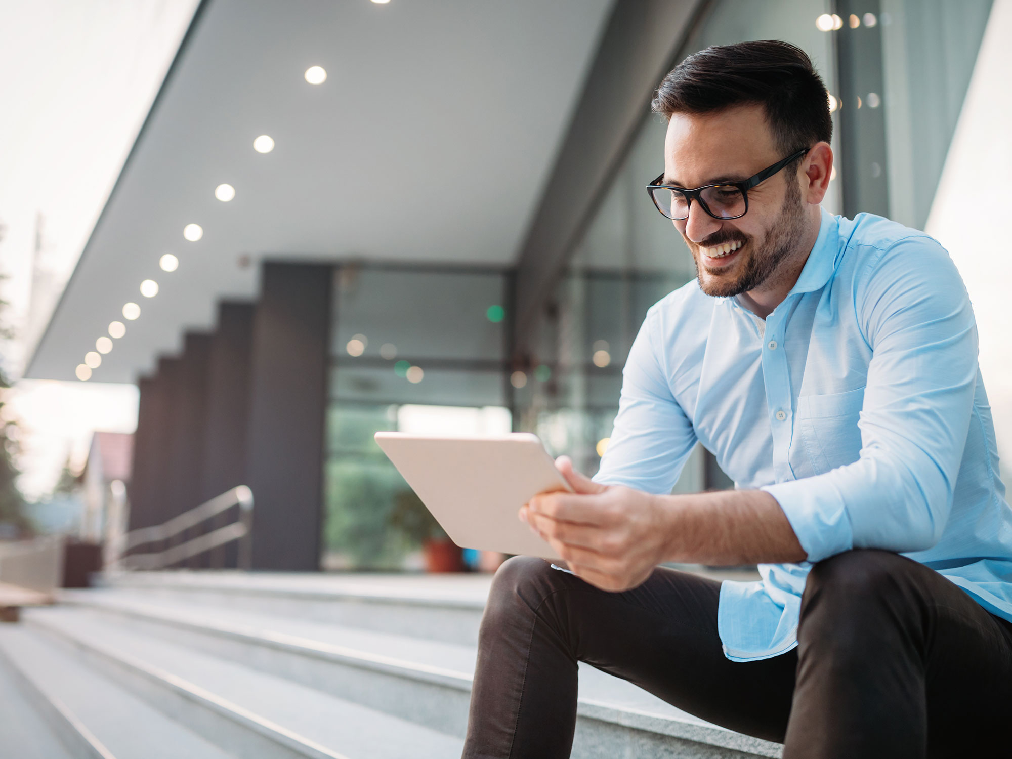 Business man looks at a laptop sitting outdoors on stairs