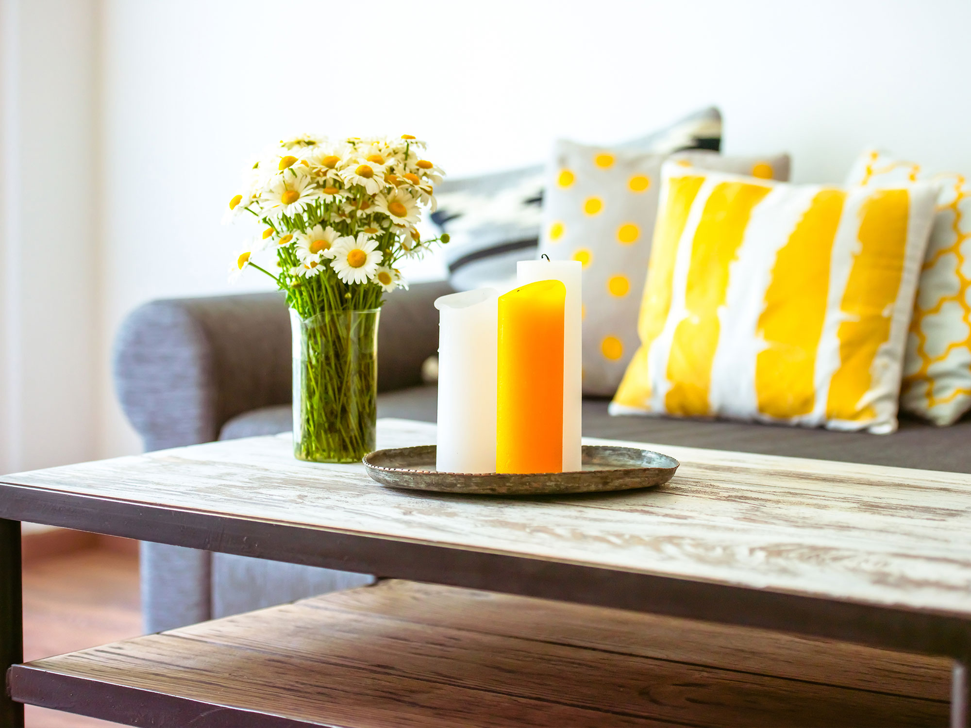 Coffee table with flowers and candles with couch in the background