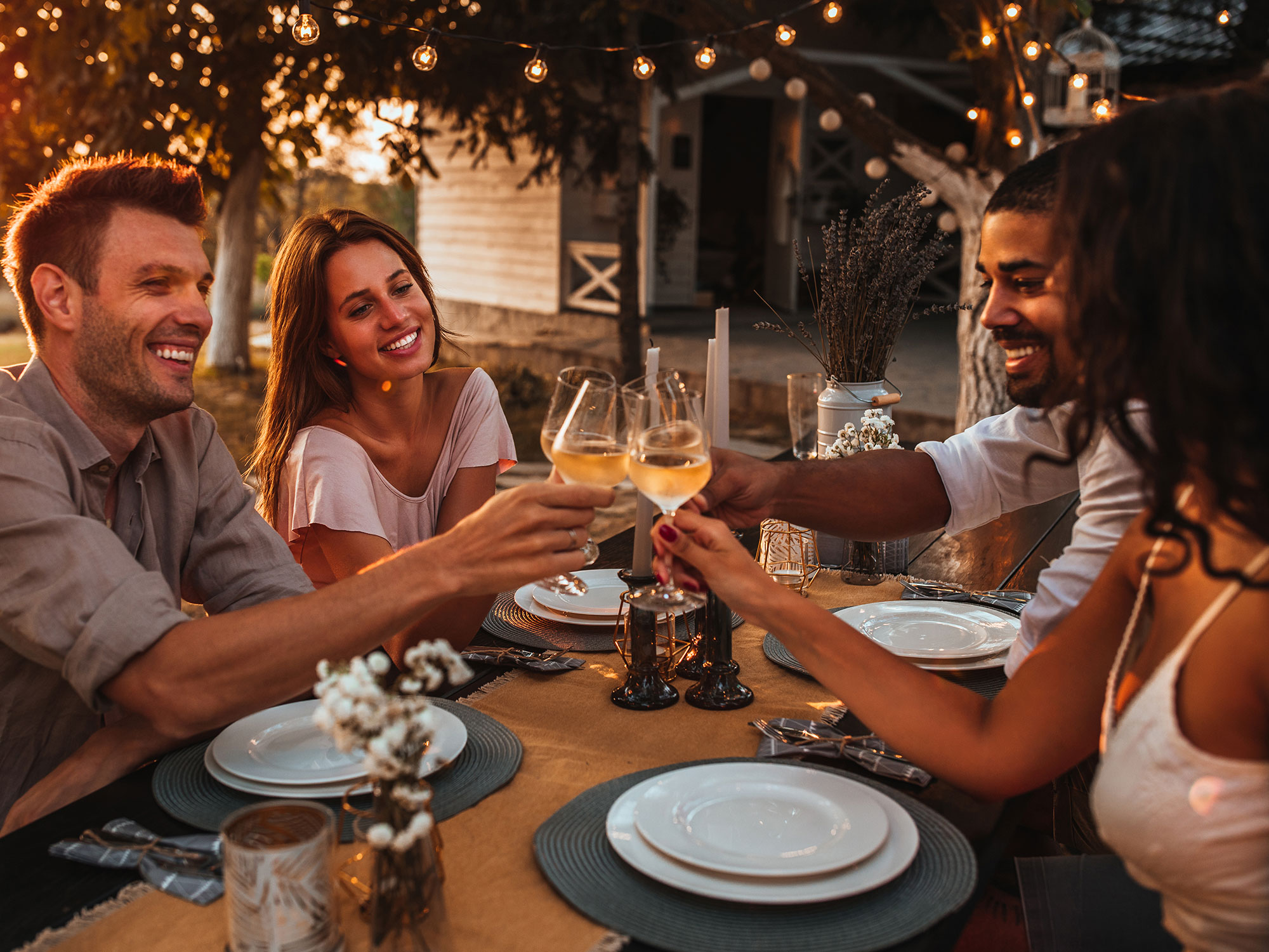 Diverse friends cheers with wine glasses at outdoor restaurant