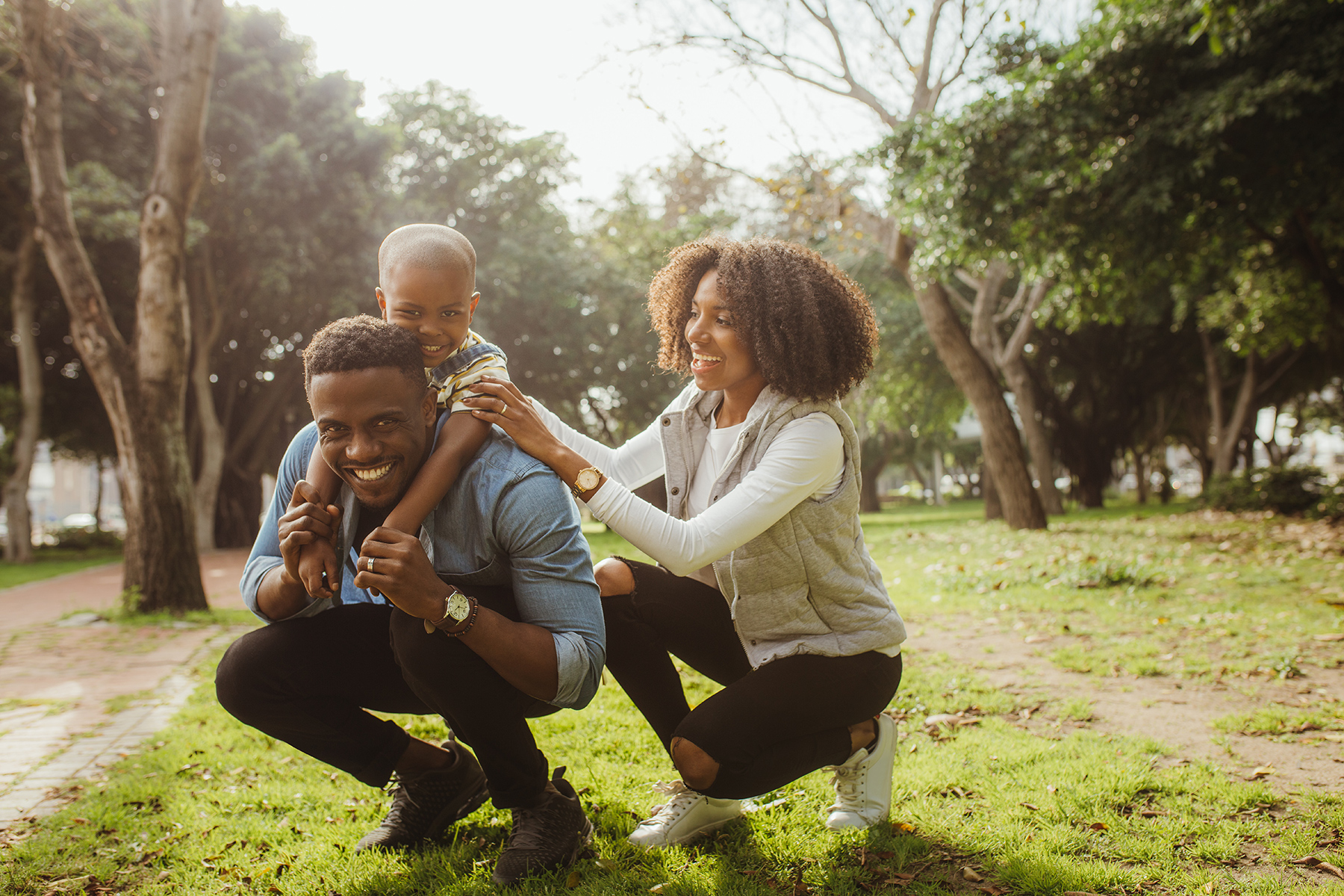 Happy family in park with father carrying child on shoulders