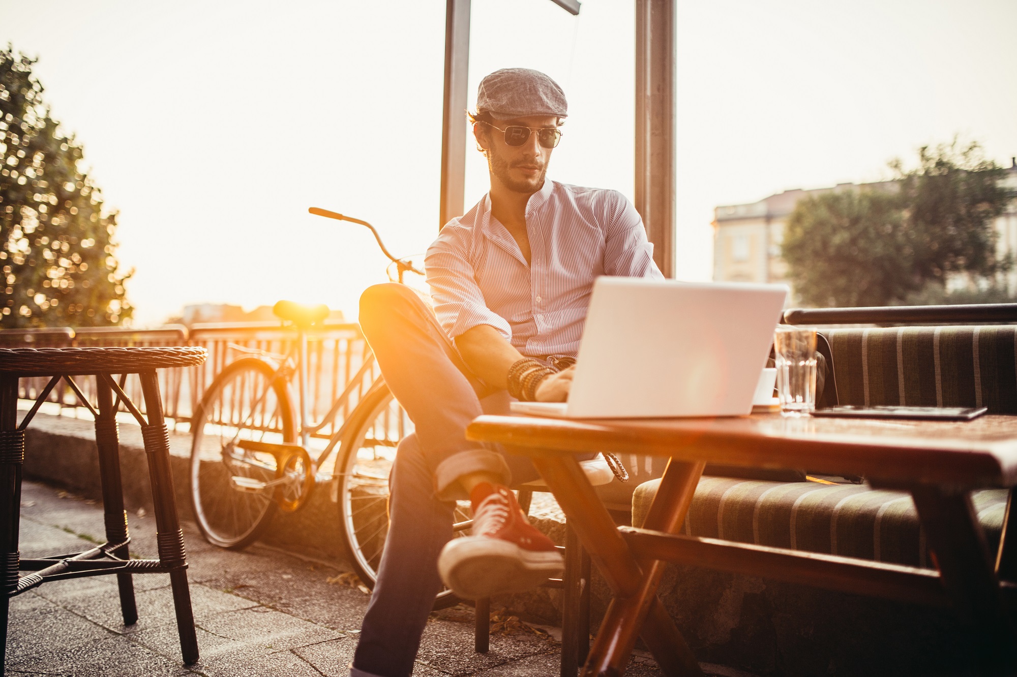 Handsome young hipster sitting in a cafe and working on laptop