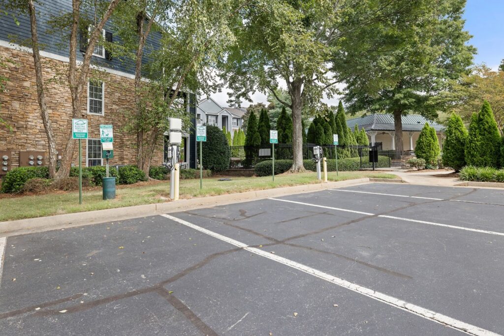 A paved parking lot with two electric vehicle charging stations installed in front of an apartment complex.