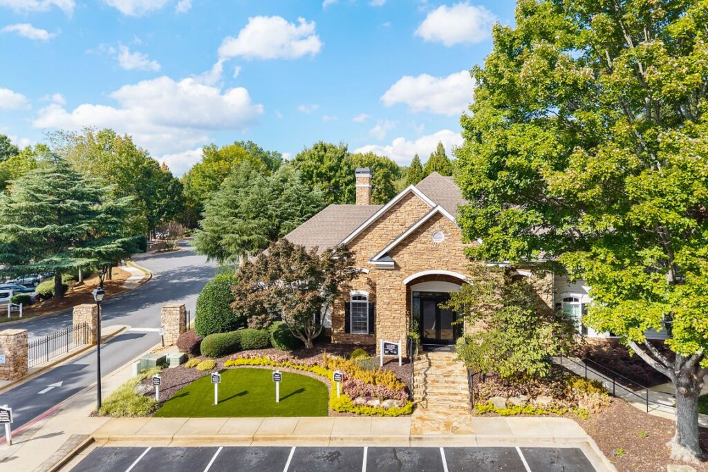 A single-story stone office building with a paved parking lot and green landscaping in the foreground.