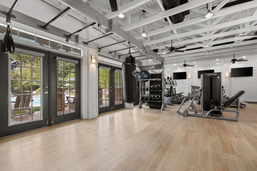 A home gym with a punching bag, exercise equipment, a pull-up bar, and glass doors opening to a patio.