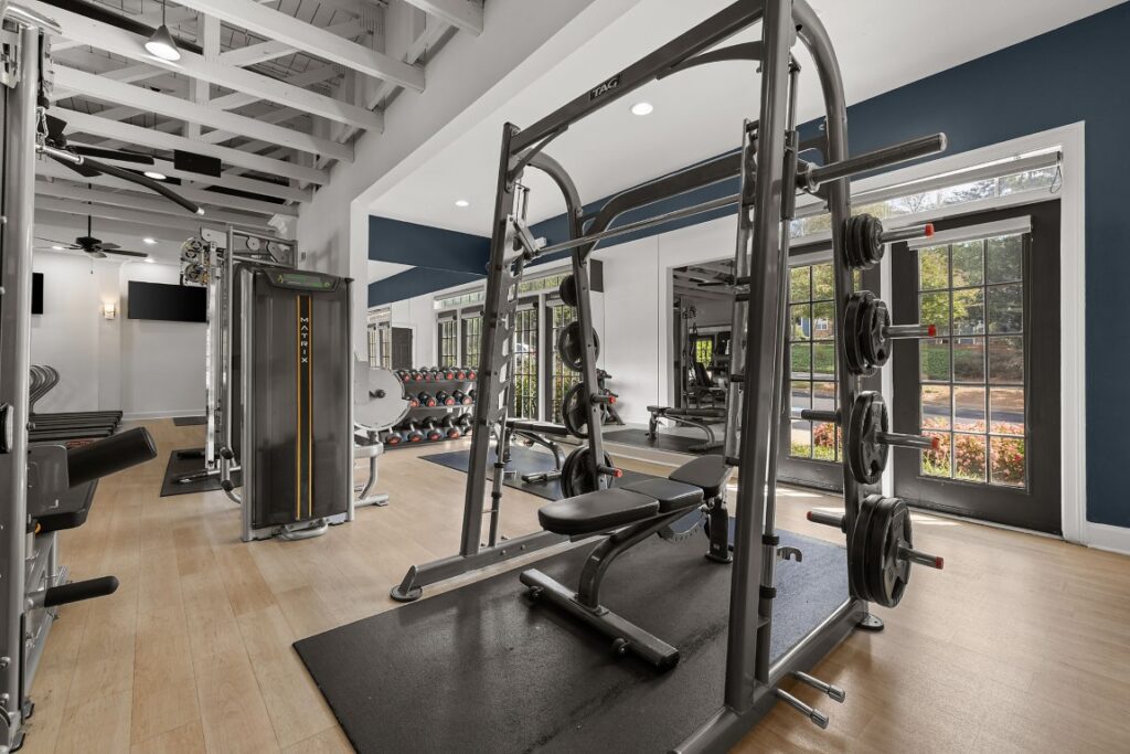 A fitness center featuring a Smith machine with a weight bench, a Matrix weight station, and rows of dumbbells.