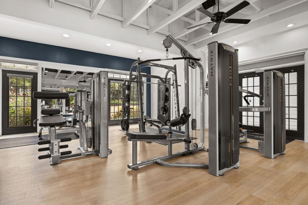 A brightly lit fitness center featuring several grey Matrix brand strength training machines on a light wood floor.