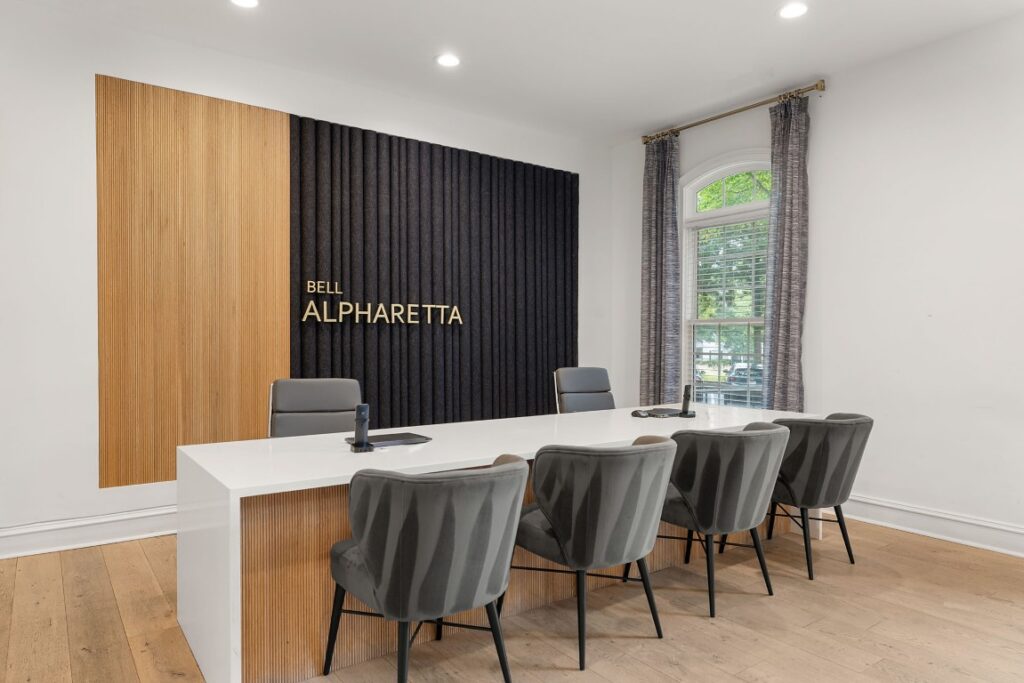 A conference table and chairs in front of a wall featuring the gold-lettered sign, Bell Alpharetta.