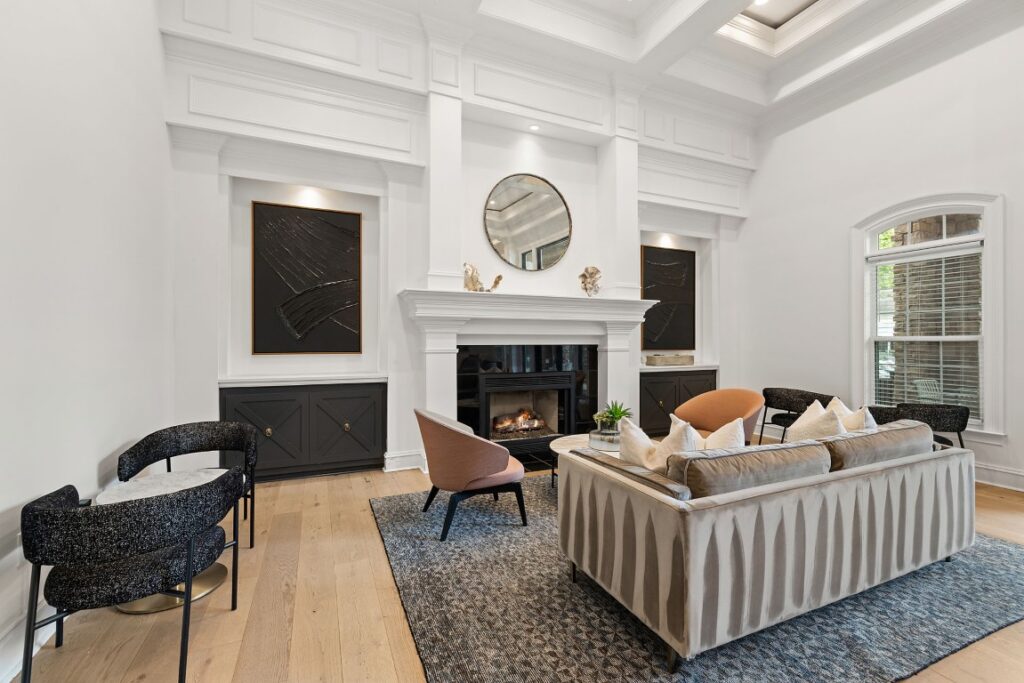 Living room with a fireplace, a grey sofa, two armchairs, and built-in black cabinets flanking the fireplace.