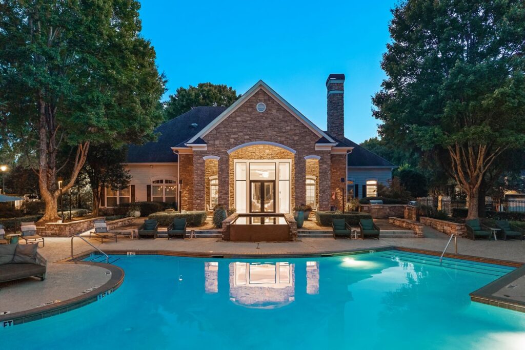 A stone clubhouse overlooking a swimming pool at twilight.