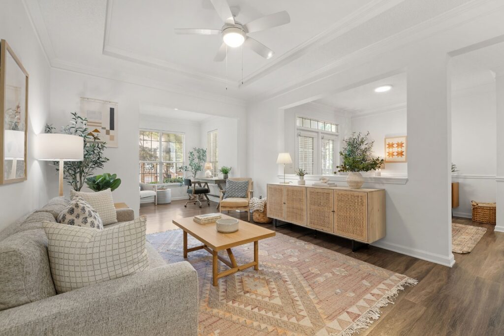 A living room with a light gray sofa, a patterned area rug, a wooden coffee table, and a sideboard with cane door panels.